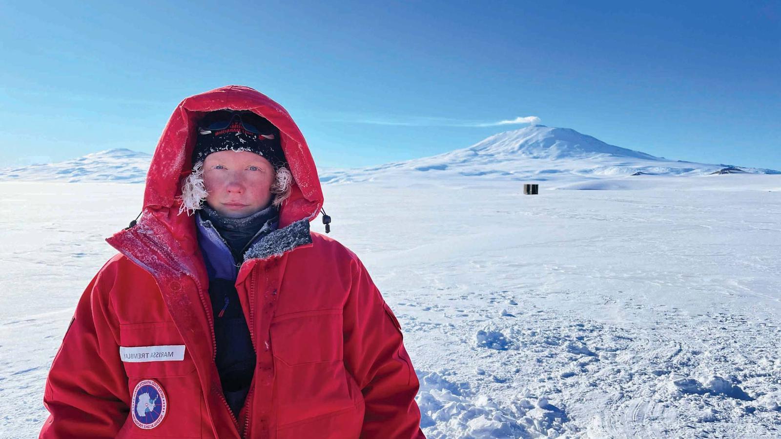 Marissa Tremblay in Antarctica. She is wearing a large red coat with the hood up.
